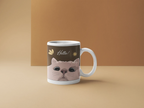 White ceramic coffee mug with cat face graphic and 'Hello!' text on front