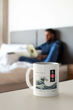 White mug with blue ocean wave print and red/black emblem, resting on a tabletop.