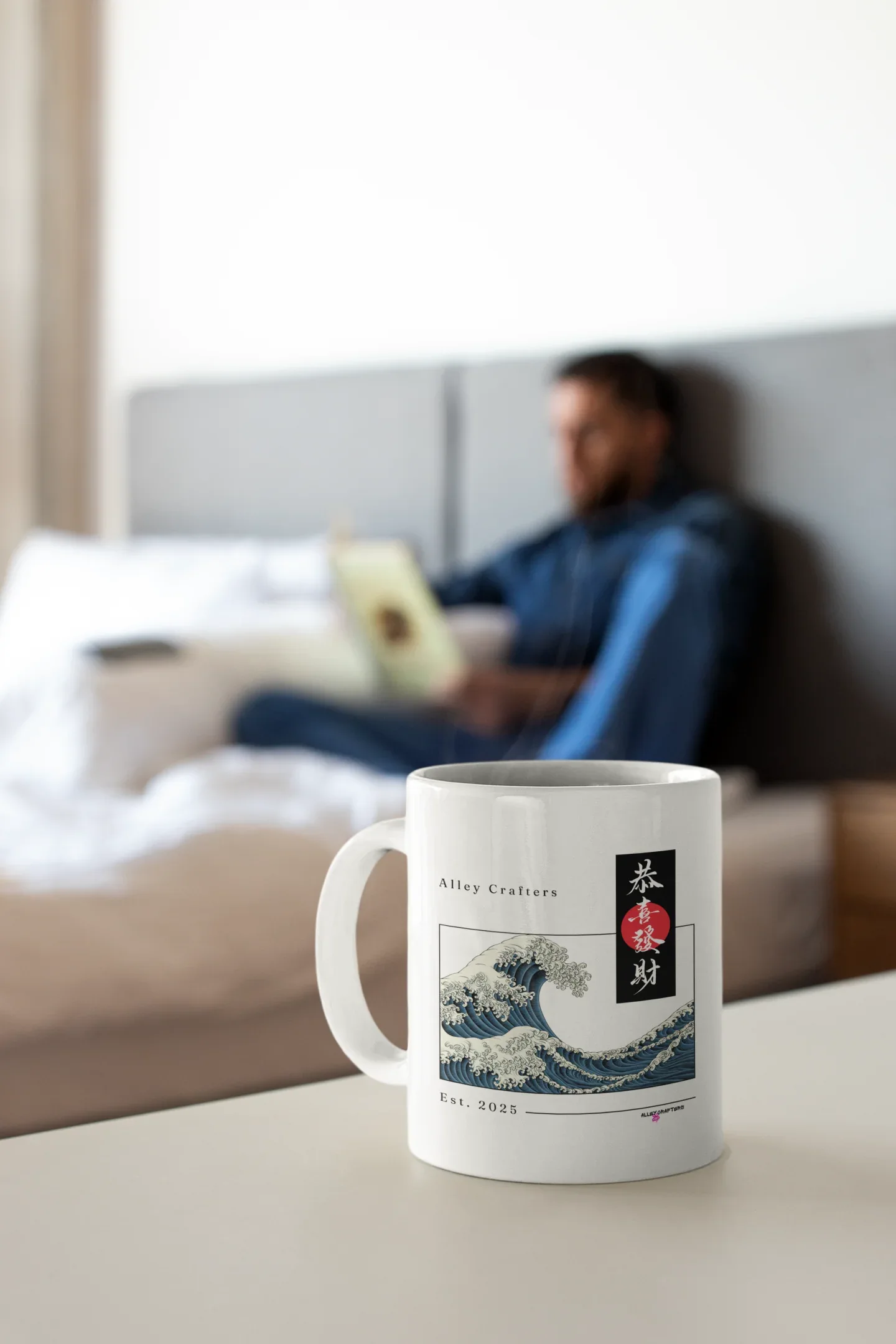 White mug with blue ocean wave print and red/black emblem, resting on a tabletop.