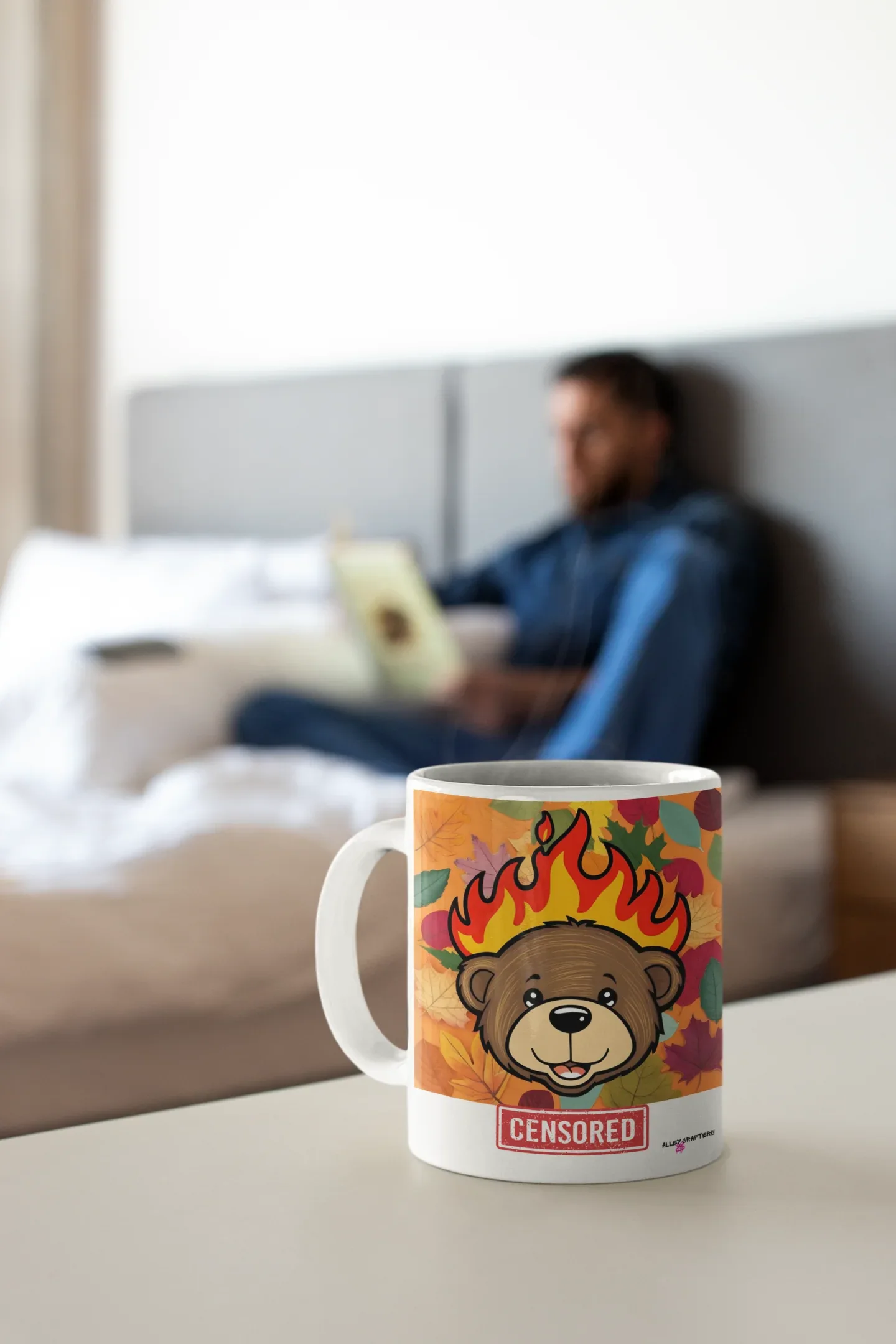 White ceramic bear mug with flames artwork and red “CENSORED” label on a tabletop.