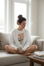 White crewneck sweatshirt worn with “Take a Deep Breath” floral text graphic.