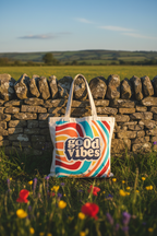 Canvas tote bag with 'good vibes' retro logo, held up in grass