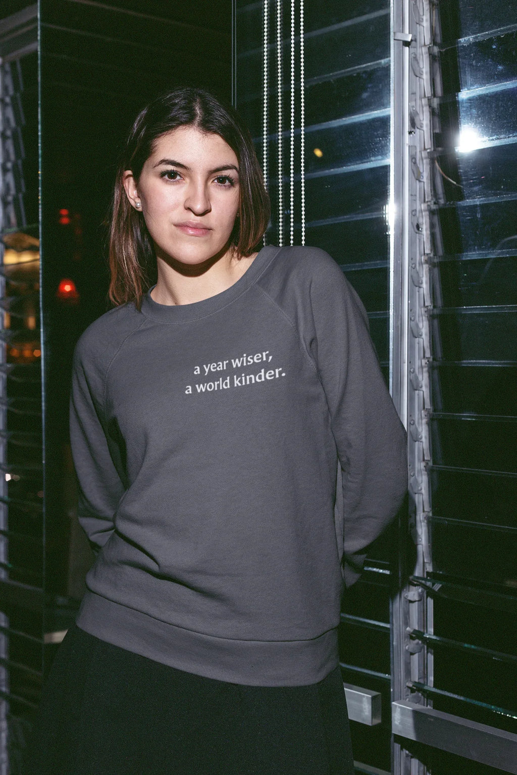 Dark gray crewneck sweatshirt with "a year wiser, a world kinder" text on chest