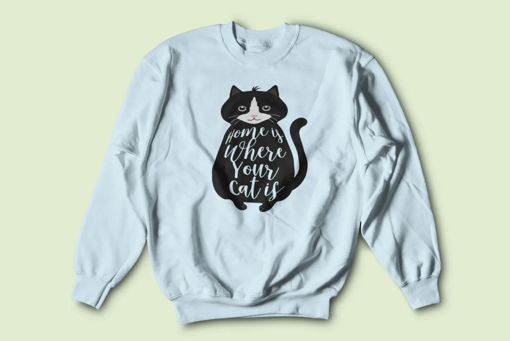 Light blue sweatshirt with long sleeves and front black cat graphic with “home where your cat is”.