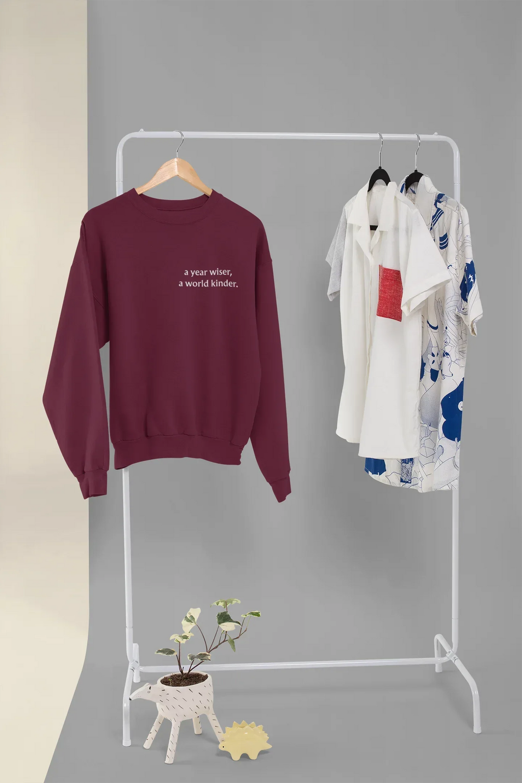Maroon crewneck sweatshirt with 'a year wiser, a world kinder.' print