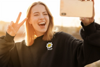 Black crewneck sweatshirt with flower smiley patch, worn by smiling person.
