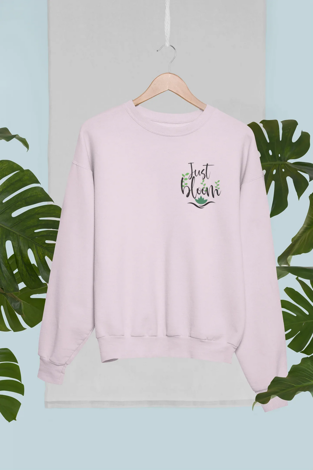 Light pink crewneck sweatshirt with small “Just Bloom” floral graphic