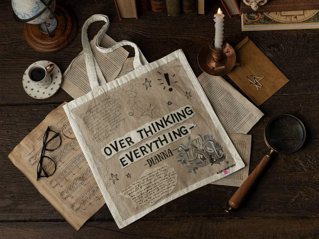 White canvas tote bag on tabletop, front print 'OVER THINKING EVERYTHING' with doodles