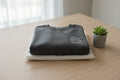 Folded dark gray crewneck sweatshirt with small chest logo