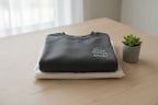 Folded dark gray crewneck sweatshirt with small chest logo
