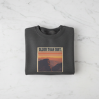 Dark heather crewneck sweatshirt with mountain sunset graphic and banner-style text
