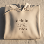 Cream delulu vibes hoodie with hood and kangaroo pocket, folded front view