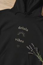 Black hoodie with 'delulu vibes' logo, small heart, drawstring hood and floral detail.