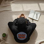 Black hoodie with circular "DELULU VIBES" chest graphic and hooded back