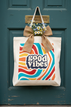 Canvas tote bag with burlap bow and 'good vibes' retro swirl logo front