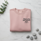 Dusty pink crewneck birthday shirt with “This is my BIRTHDAY shirt” print.