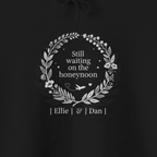 Black hoodie print: 'Still waiting on the honeymoon' wreath with 'Ellie' & 'Dan' names
