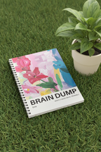 A5 spiral notebook with floral “BRAIN DUMP” cover, resting on grass