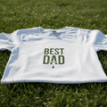 White T-shirt close-up: green “BEST DAD” graphic on the front chest