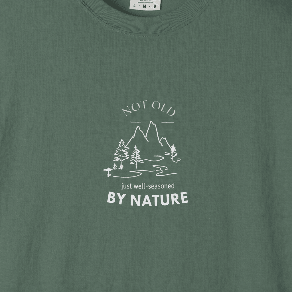 Forest green graphic T-shirt with mountain and trees line art and “BY NATURE” text