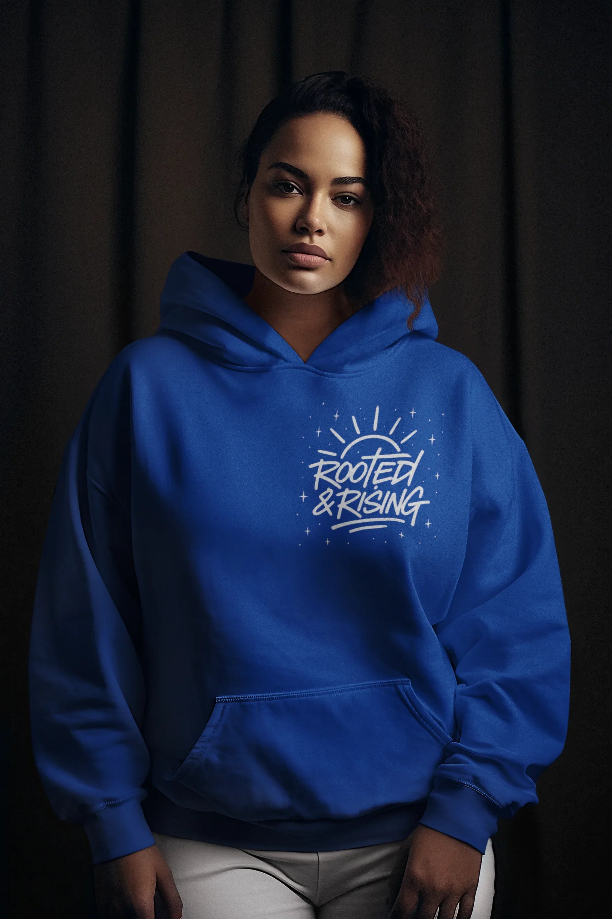 Blue pullover hoodie with hood up and 'Rooted & Rising' chest graphic