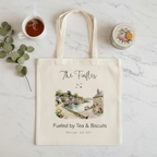 White canvas tote bag with personalized script name and watercolor town-by-water print