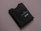 Black crewneck sweatshirt folded, with Wanderlust logo and badge on chest