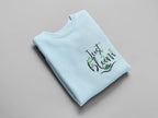 Light blue crewneck sweatshirt with floral “Just Bloom” graphic