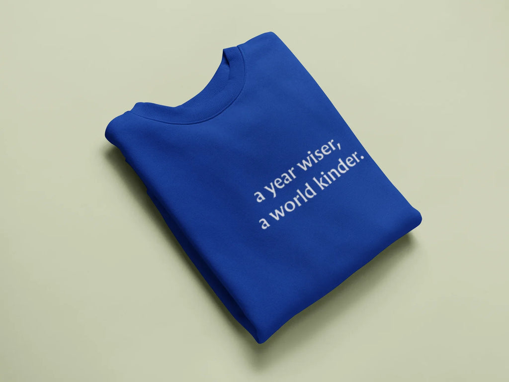 Blue crewneck sweatshirt, "a year wiser, a world kinder" text print on chest