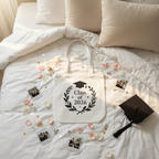 White tote bag with Class of 2026 wreath graphic on bed, top view