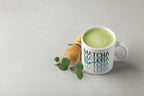White ceramic matcha mug with green MATCHA text, filled with green tea