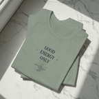 Sage green crew-neck T-shirt stacked, showing “GOOD ENERGY ONLY” chest graphic