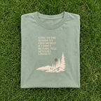 Sage green hiking T-shirt with woods scene graphic and quote text on front