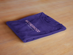 Purple heavy cotton maternity T-shirt, folded, with "Motherhood in Progress" print