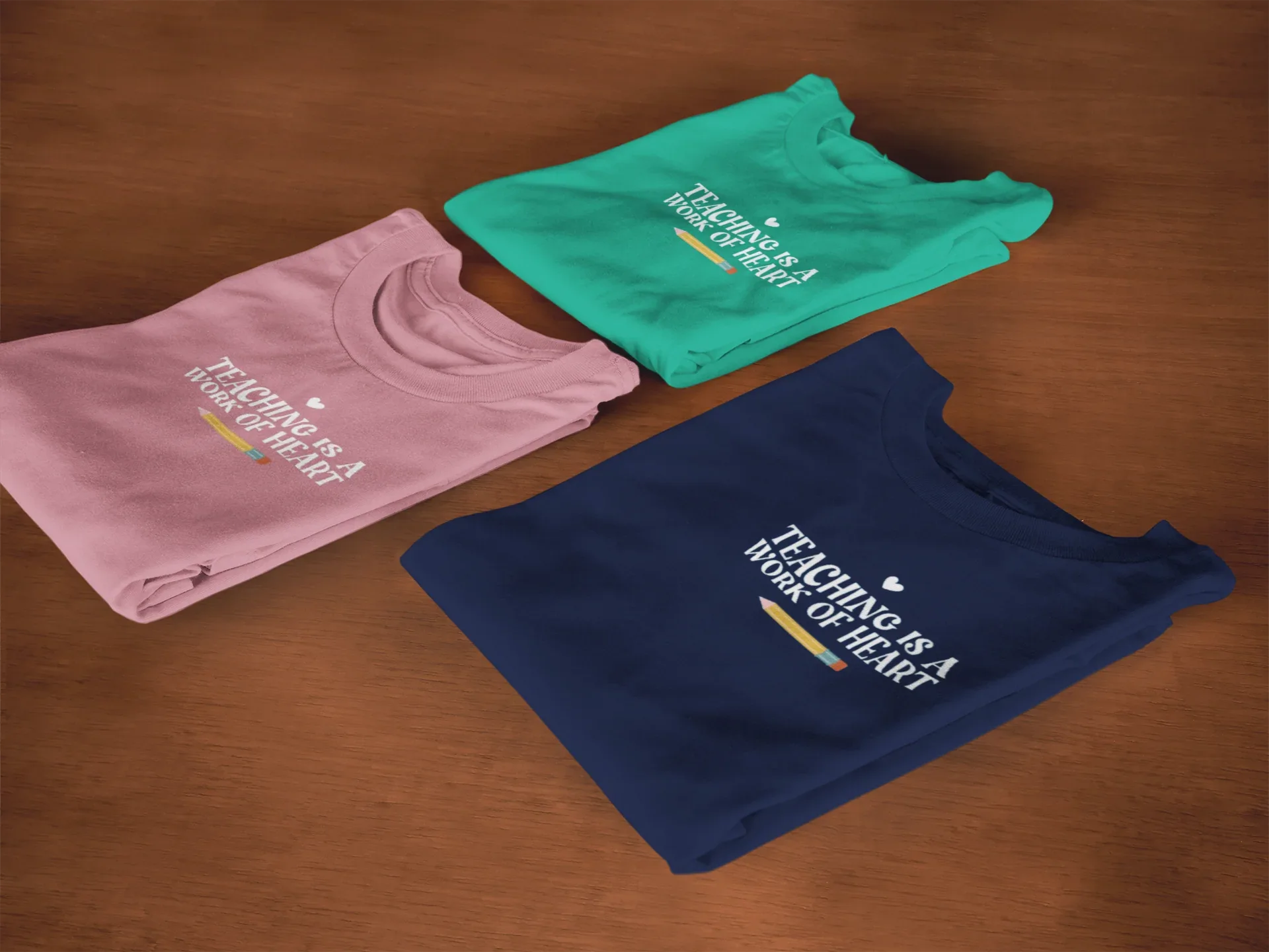 Set of folded unisex T-shirts: mauve, teal, and navy, each with heart slogan print