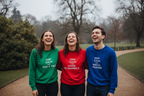 Three crewneck sweatshirts in green, red, and blue with printed slogans on front