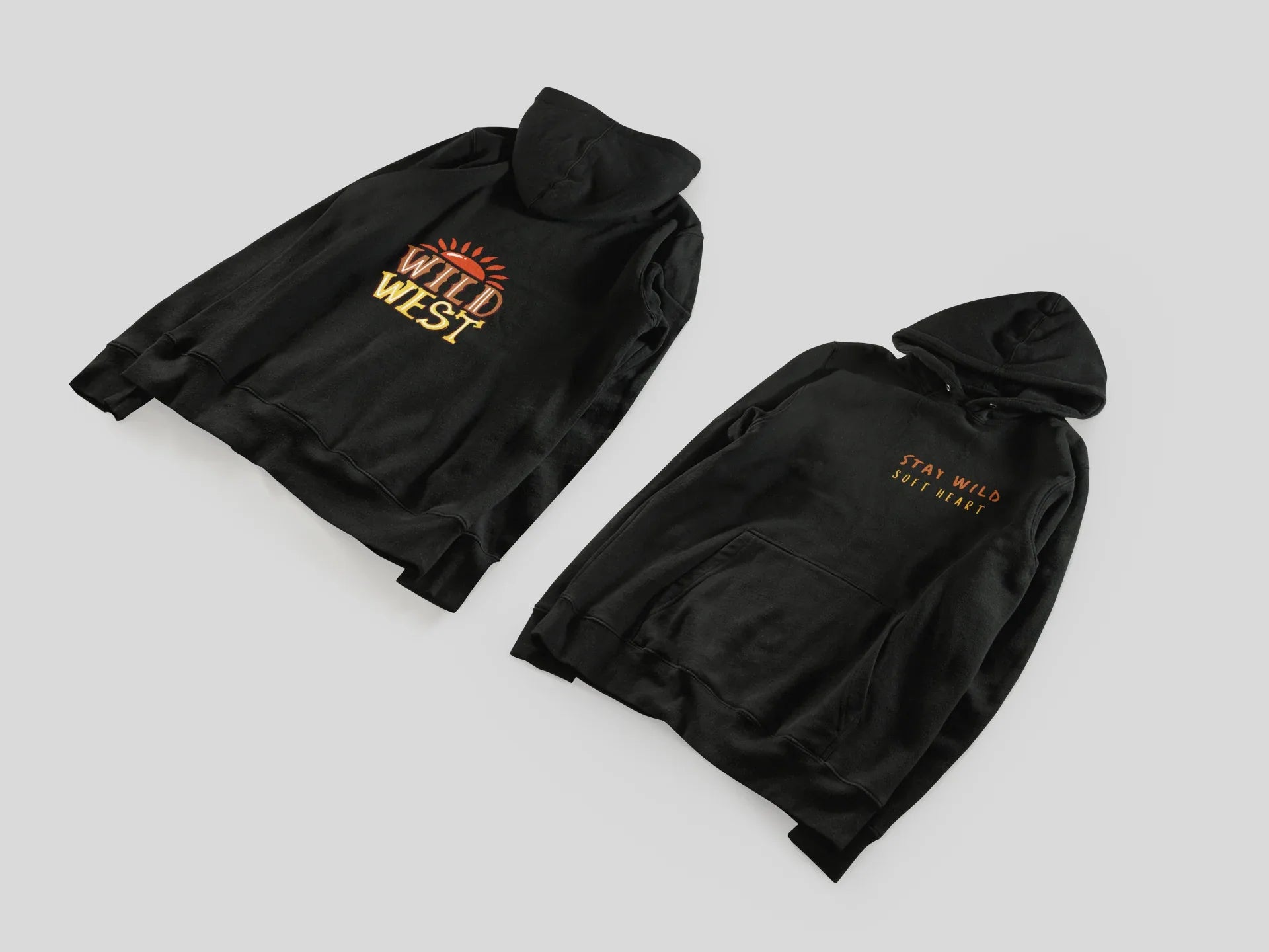 Black hoodie pair folded flat: Wild West emblem and Stay Wild Soft Heart text