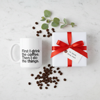 White ceramic coffee mug with quote text beside a wrapped gift box and red bow.