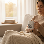 White ceramic coffee mug with quote text in a cozy living room setting.