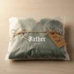 Gray folded hoodie with 'Father' print and gift tag tied with twine