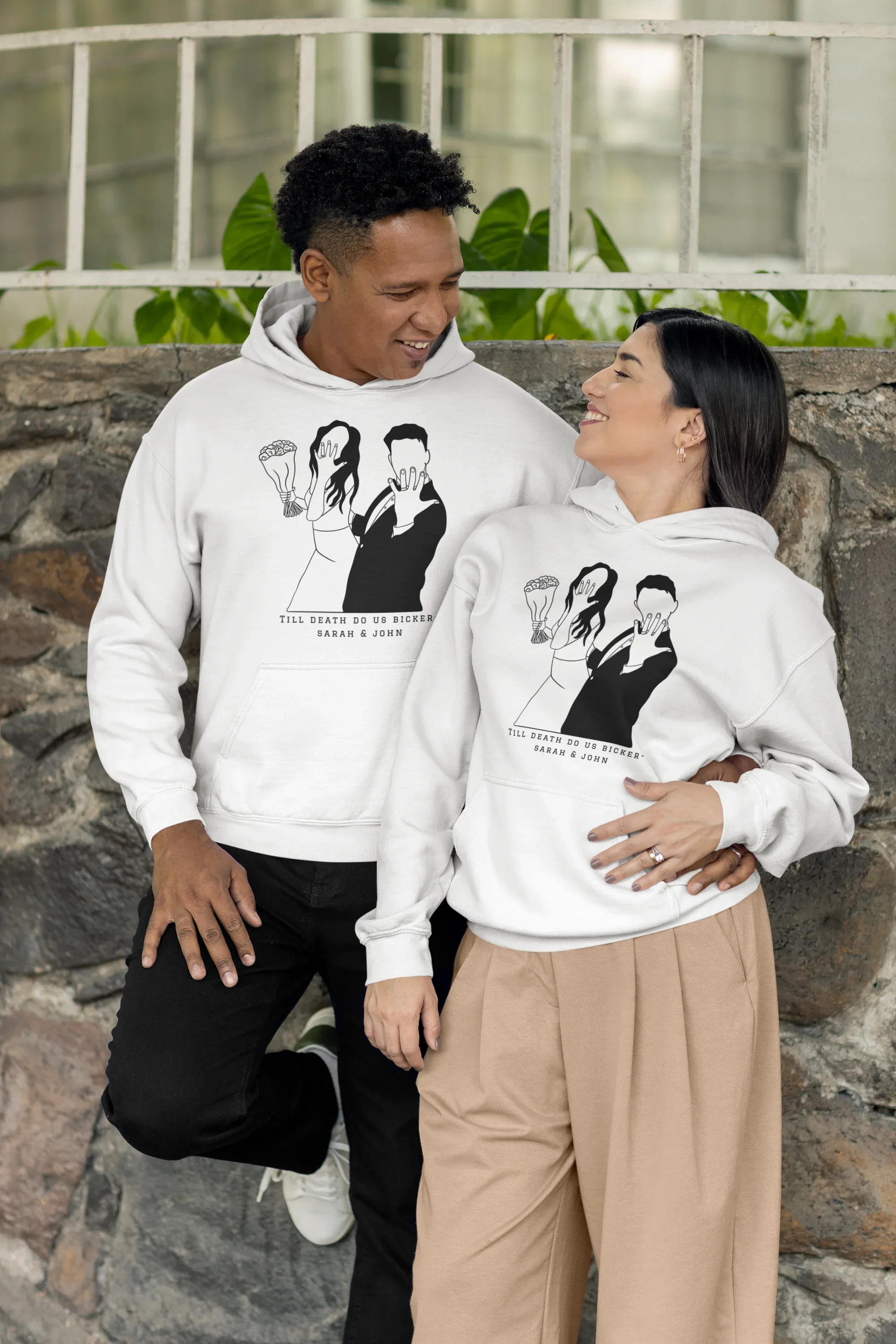 White couple graphic hoodies on two people outdoors, front prints with hood and pocket.
