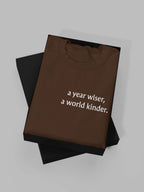 Brown crewneck sweatshirt with "a year wiser, a world kinder" text print