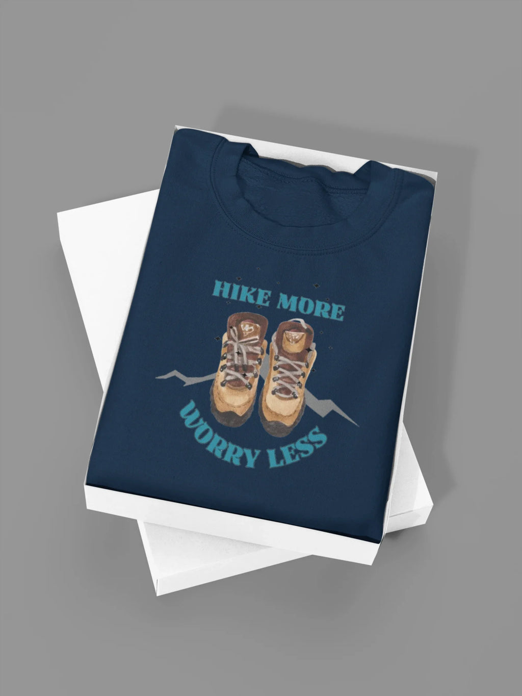 Navy crewneck sweatshirt folded with 'Hike More, Worry Less' hiking boots graphic