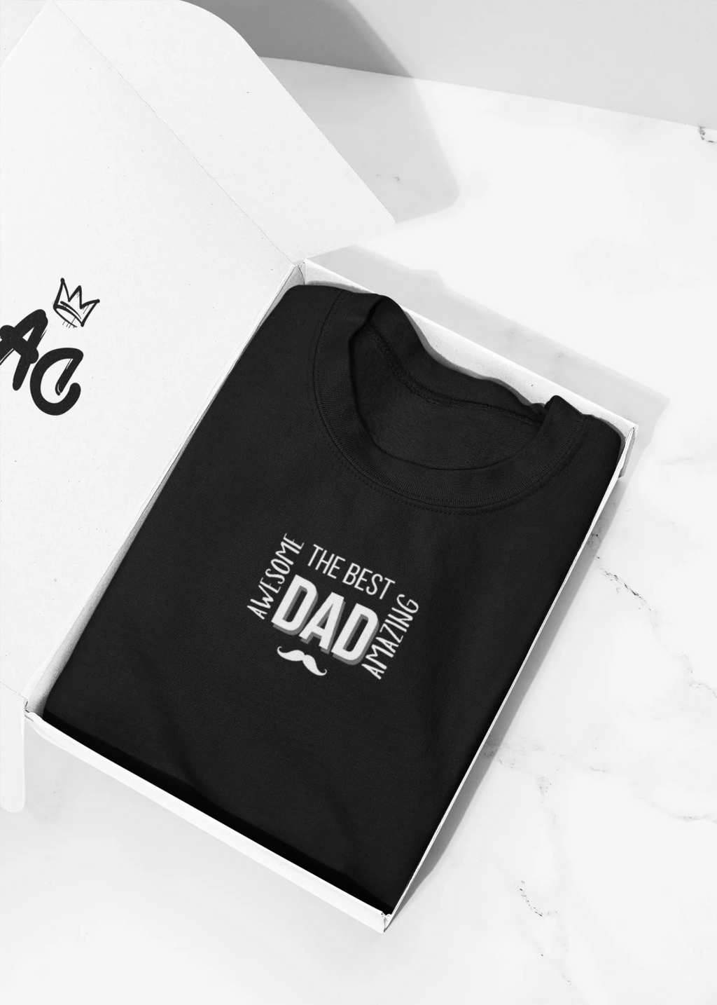 Folded black heavy cotton T-shirt in a box, featuring “The Best Dad” mustache graphic.