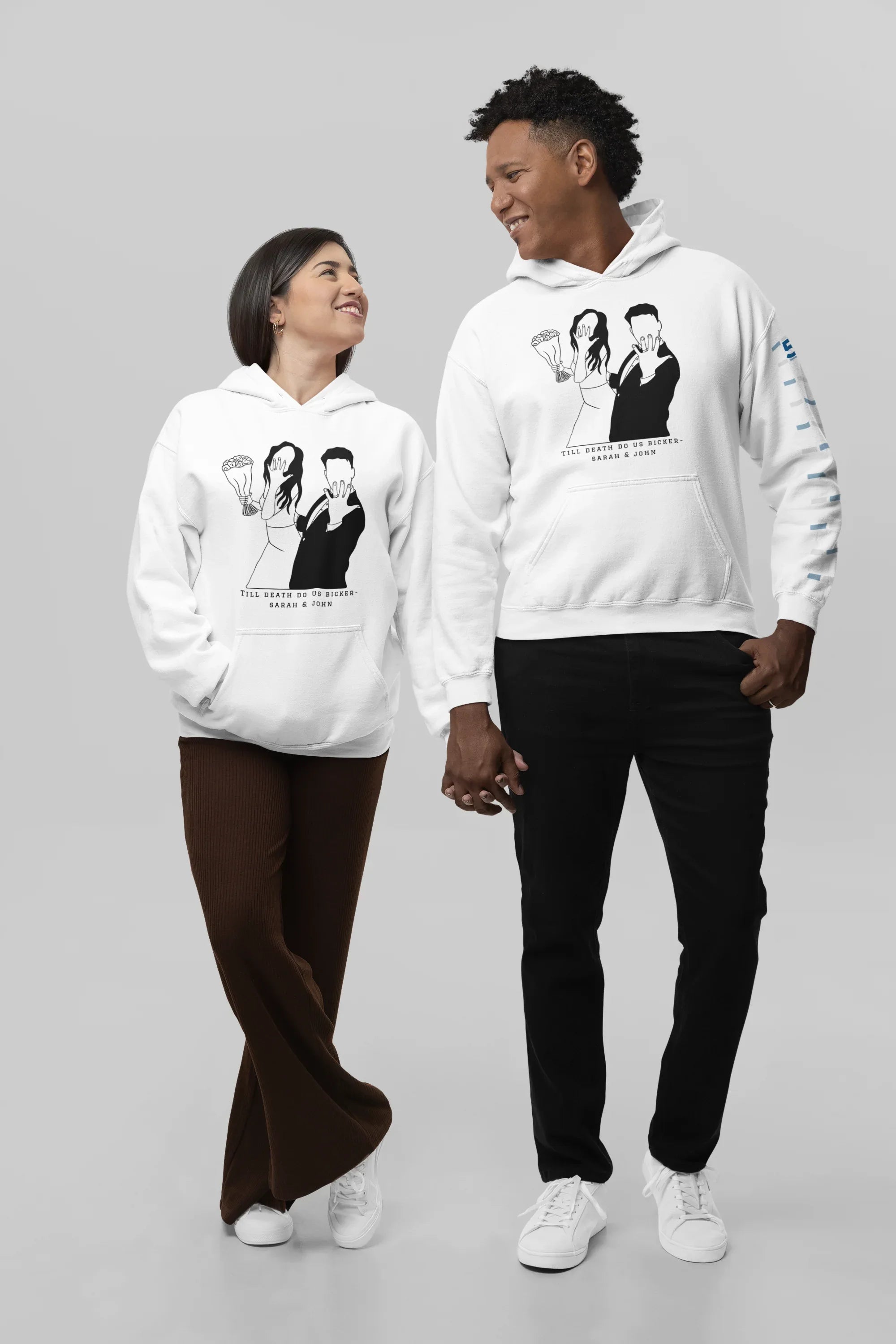 White couple graphic hoodies on two people, front prints and pullover hood.