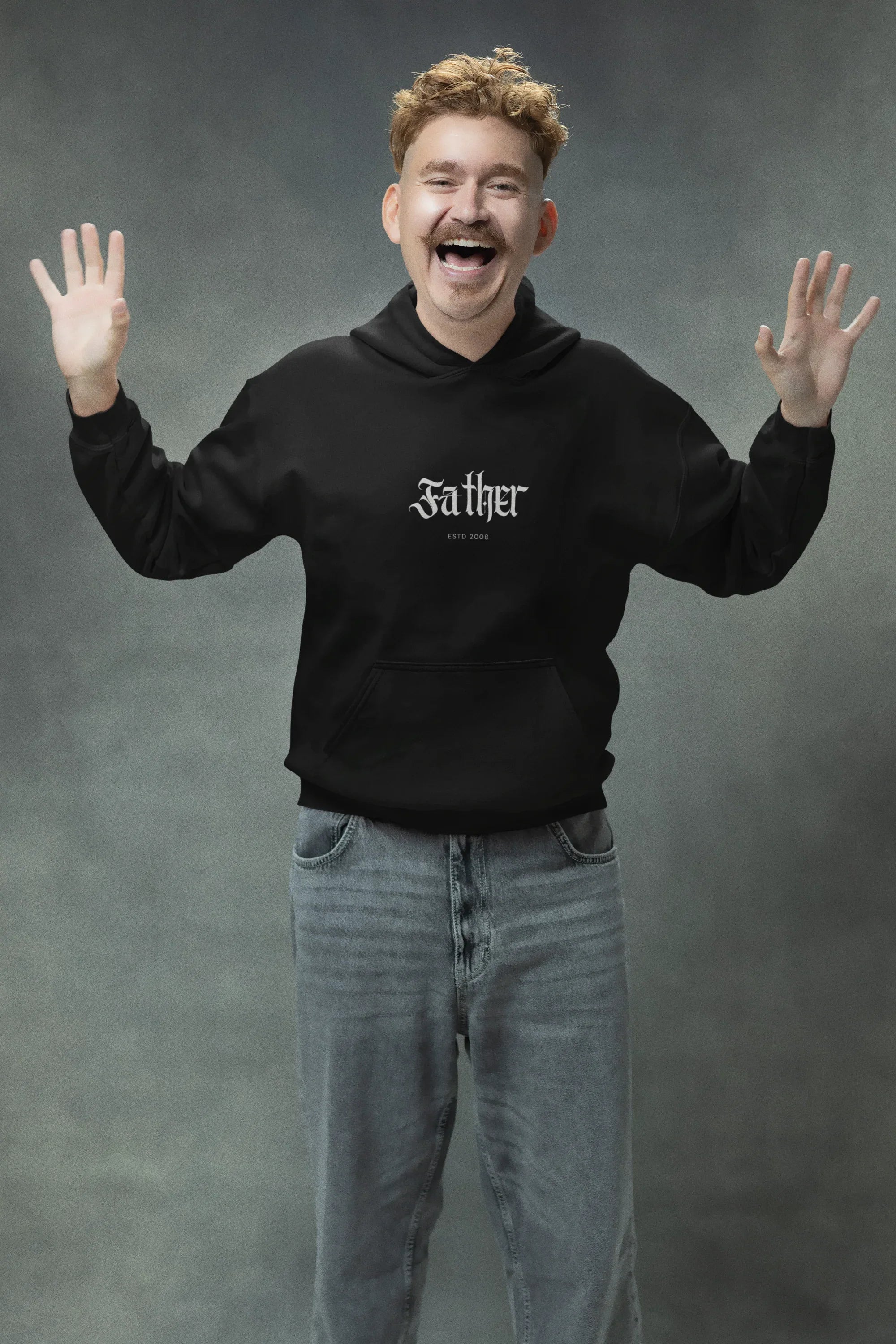 Man wearing a black pullover hoodie with front pocket, hood drawstrings, and chest logo.