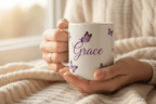 White mug with purple butterfly border and name Grace, held in hands