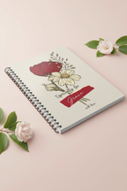 A5 floral journal notebook on pink surface, beige cover with red name label