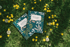 Teal A5 spiral notebook with botanical cover lying on grass with label
