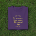 Purple T-shirt with gold “Grandma: Snacks on Demand” and “Nana Pat”